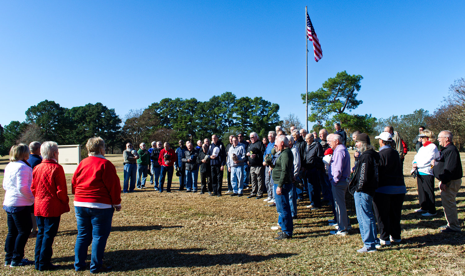 A group of military veterans gathers at the flag pole at the Mineola Country Club Friday morning for the singing of the National Anthem, along with a prayer and the Pledge of Allegiance, before teeing off in the club’s annual veterans tournament (postponed from Monday, Nov. 11 due to inclement weather). Leading the singing were Shirley Frazier, Chris Black and Donna Kinstley.